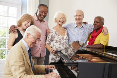 Group of seniors standing by piano and singing together