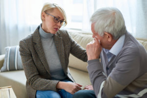 Female psychiatrist comforting senior man