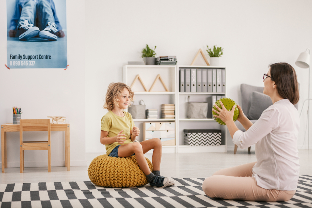 Young female therapist playing with a happy orphaned boy during a therapy session concept