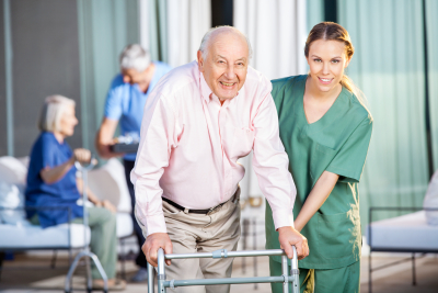 happy female caretaker helping senior man